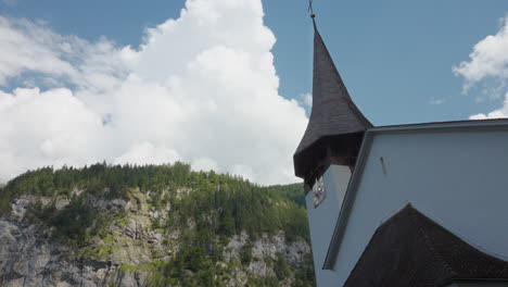 chapel steeple with stunning white fluffy clouds casting shadows over pine tree mountain side