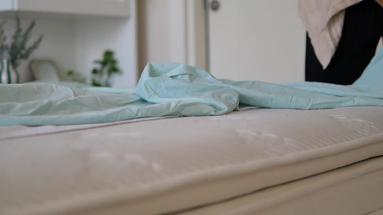 Bedroom scene with bed, sheets, and a person in the background