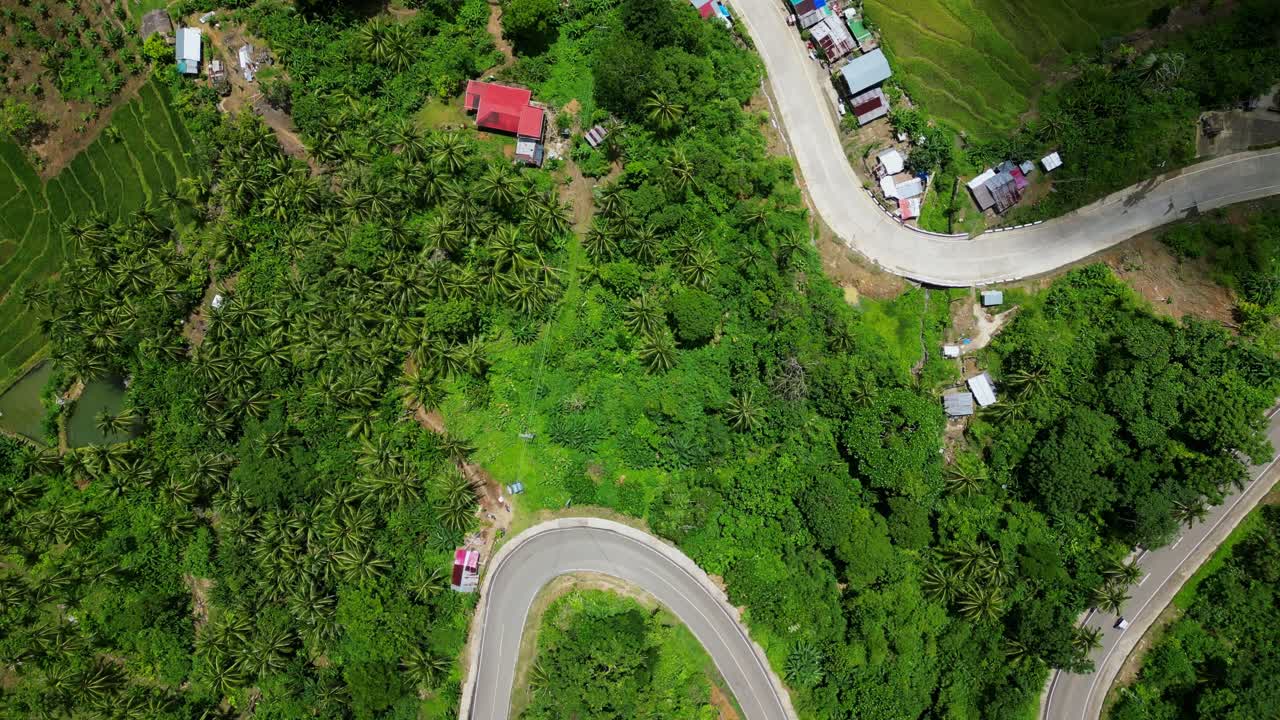 Aerial top-down view of serpentine roads along lush mountains and local villages in tropical island. Bagumbayan, Bato, Catanduanes.