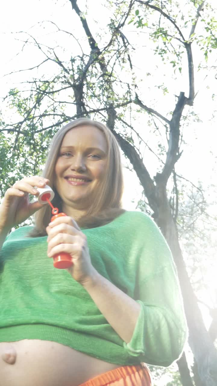 Pregnant woman blowing bubbles outdoors