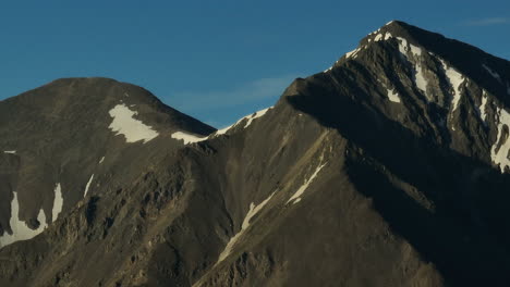 Aerial-cinematic-drone-sunrise-sunlight-early-morning-shadows-Grays-and-Torreys-14er-Peaks-Rocky-Mountains-Colorado-stunning-landscape-view-mid-summer-snow-on-top-zoom-slowly-circle-right-movement