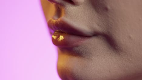 cerca de los labios de la mujer con un hermoso lápiz labial sonriendo contra un fondo rosa, toma de estudio