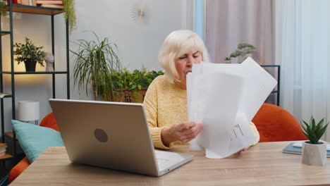 Stressed-senior-woman-looking-at-unpaid-bank-debt-loan-doing-paperwork-planning-budget-throws-bills