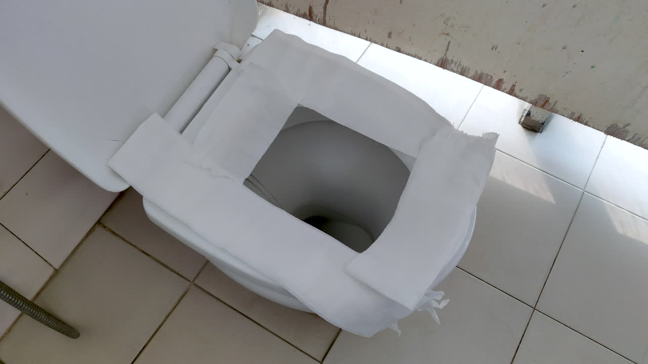 asiento de inodoro de cerámica de un inodoro público cubierto con papel higiénico