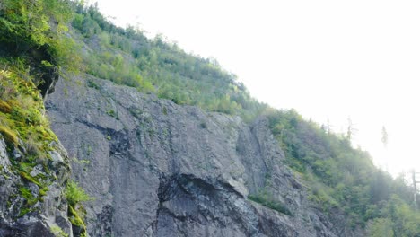 Slow-aerial-reveal-of-rocky-mountain-wall-on-sunny-day,-Nature-concept