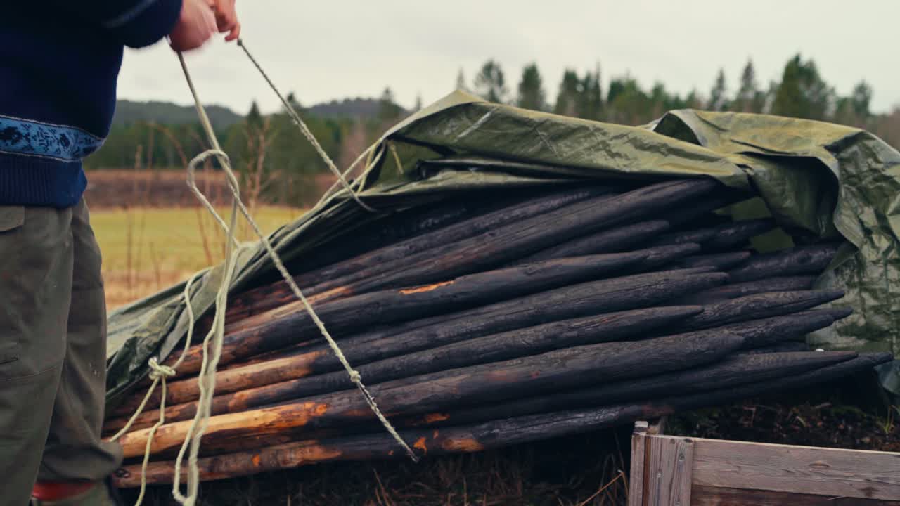 Charred Wooden Stakes are Stacked and Secured Under a Tarp, Ready For Use or Storage - Close Up