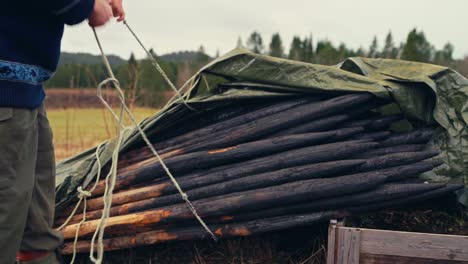 charred wooden stakes are stacked and secured under a tarp, ready for use or storage - close up