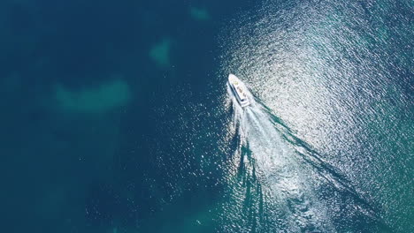 white boat sailing on a blue sea with sun light