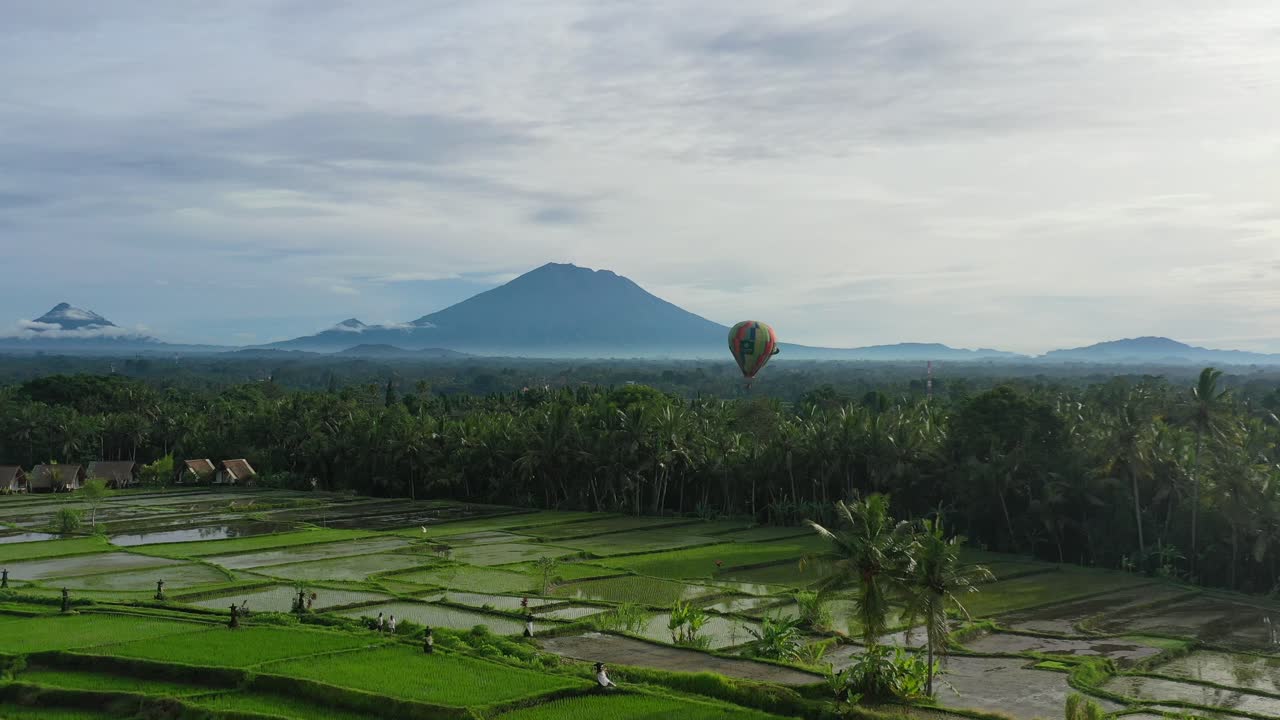 Mongolfiera che vola sopra una risaia di Ubud Bali con vulcano all'orizzonte, vista aerea