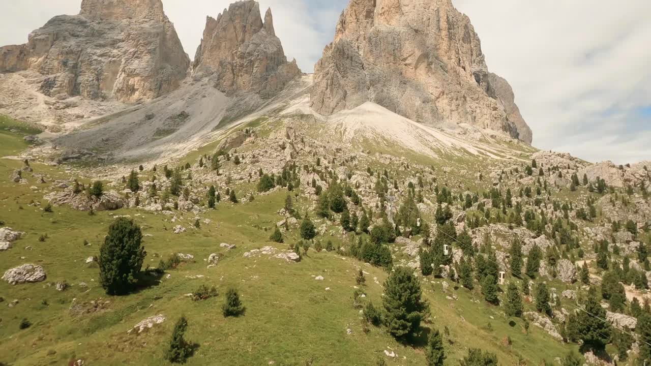 FPV drone heads to Italian Dolomites' Sasslong mountain, soaring above rock formations and an old cable car on its ascent