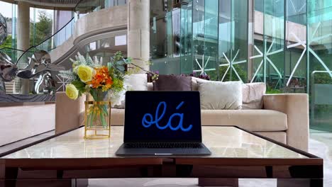 macbook laptop screen displaying "olá" in a luxurious mansion