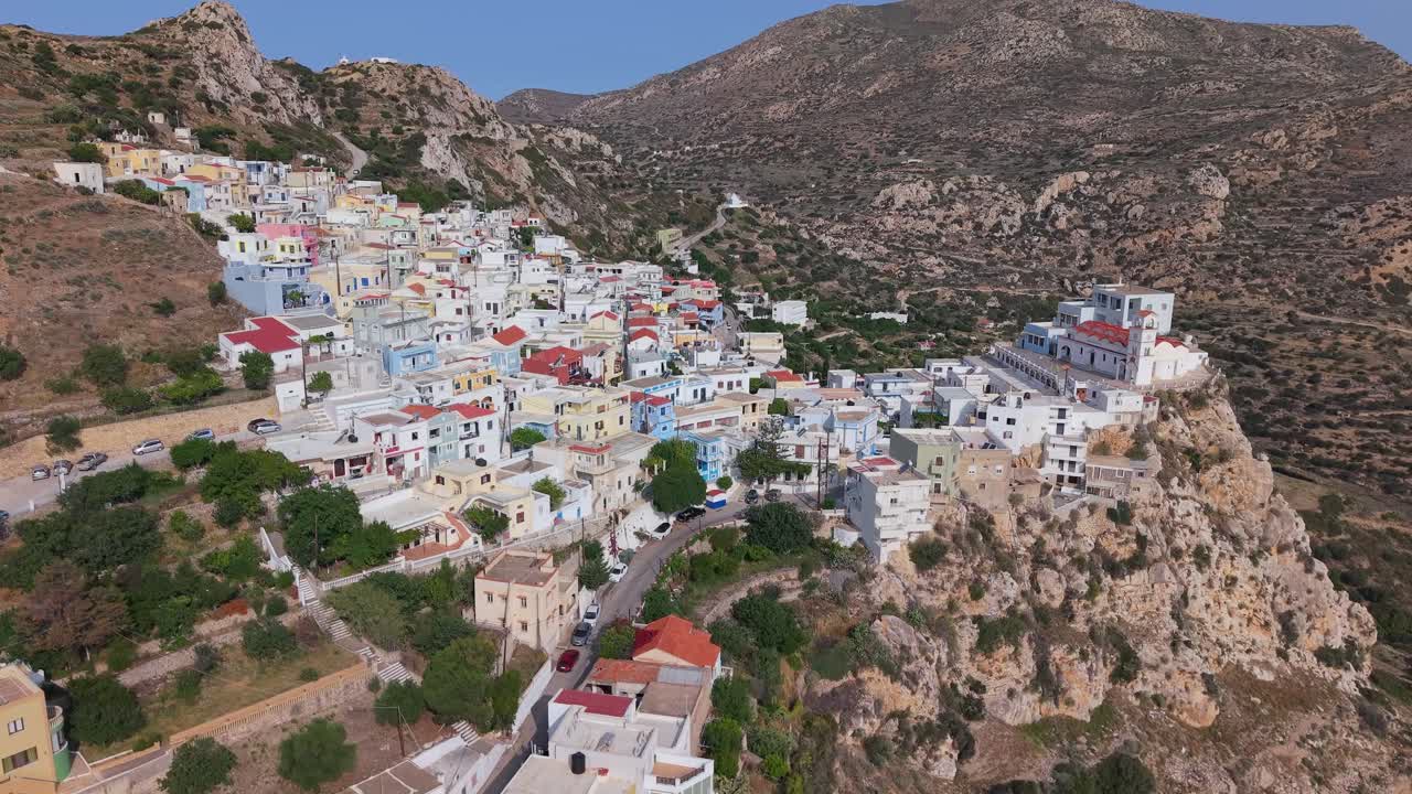Aerial drone footage revealing the vibrant, colorful houses of Menetes Village on Karpathos Island, Greece. Scenic view of traditional architecture and Mediterranean charm