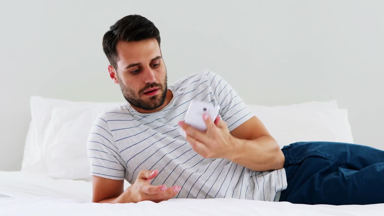 hombre usando teléfono móvil en la cama en el dormitorio