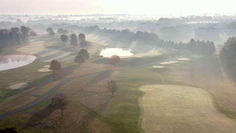 Antena-Cinematográfica-Del-Amanecer-Quemando-La-Niebla-Sobre-El-Magnífico-Campo-De-Golf-Del-Club-De-Campo,-Hojas-De-Otoño