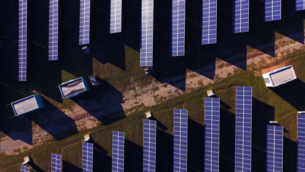 Motivo ravvicinato di file verticali di pannelli solari sotto la luce del sole. Vista aerea di pannelli fotovoltaici fittamente disposti e orientati verticalmente, con una texture a strisce alternate illuminate e scure nei toni del blu.