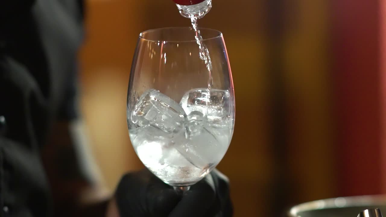 Barman che versa una bevanda alcolica in un bicchiere al rallentatore
