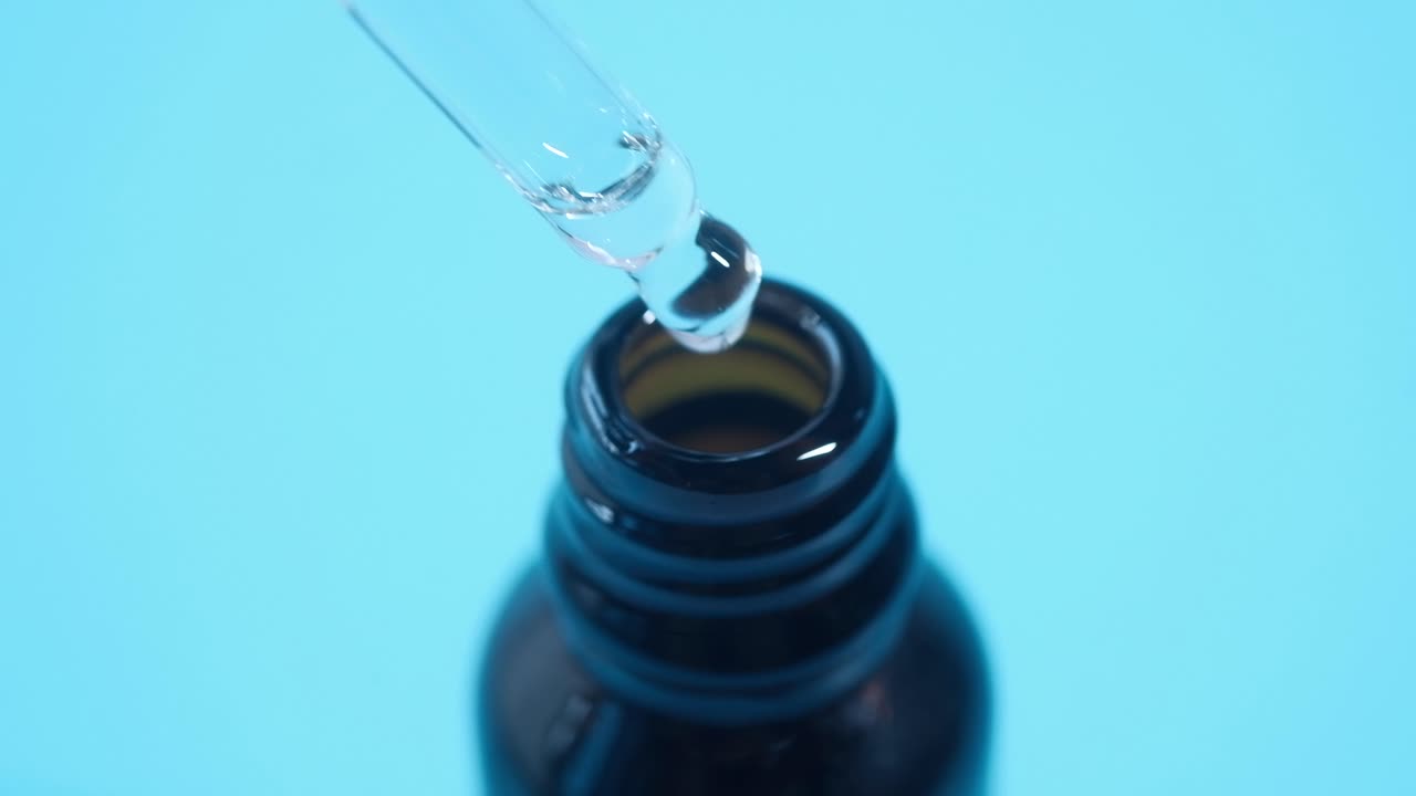 Dropper pouring liquid into a dark glass bottle
