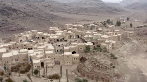 a drone shot of an old middle eastern town between mountains with a bazaar full of people