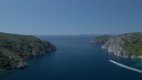 Cinematic-rotating-up-high-4K-drone-clip-over-the-tropical-blue-waters-of-Toroni-in-Chalkidiki-with-some-boats-passing-by