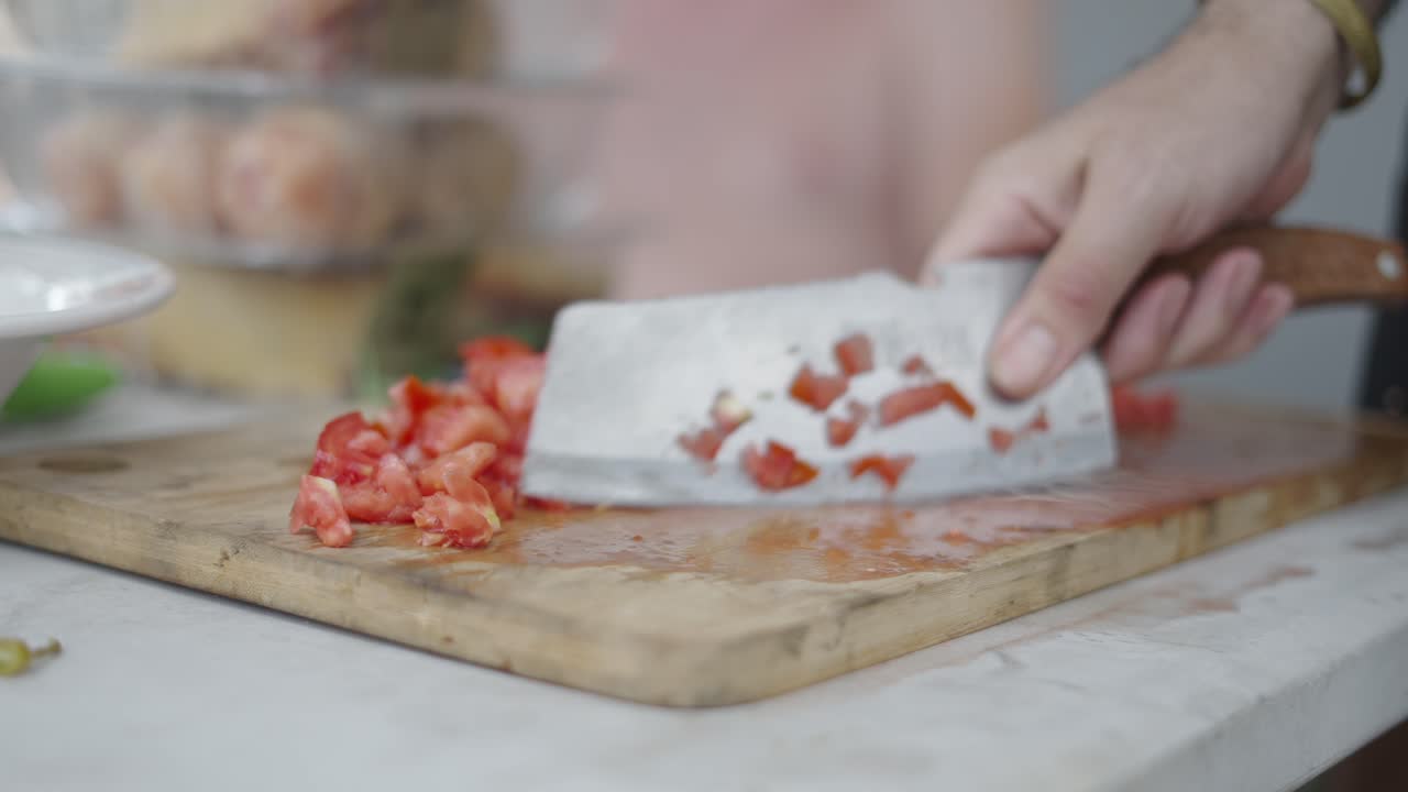 Close-up of hands chopping tomatoes on a cutting board