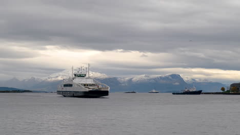 Ferry-Cruzando-Las-Aguas-Hacia-Mold-Quay-Con-Montañas-Nevadas-En-El-Fondo,-Noruega