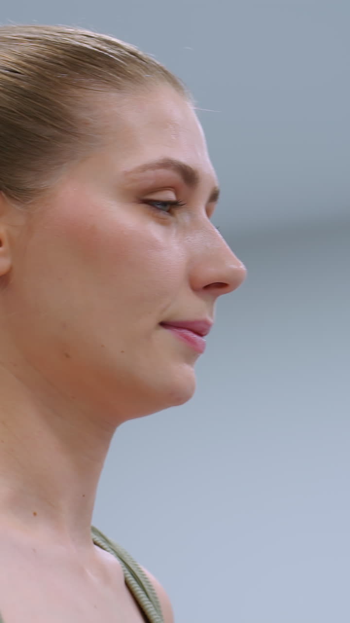 primer plano de mujeres haciendo ejercicio, levantándose de las agachadas, respirando profundamente mientras la iluminación brillante ilumina la escena, centrándose en su concentración y movimientos controlados en una sesión de fitness