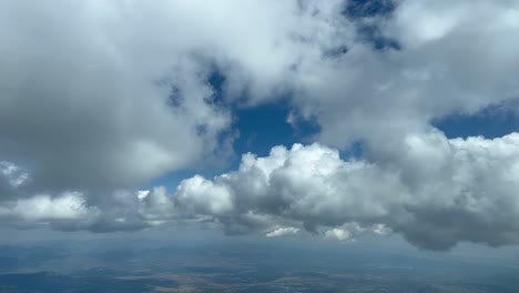 aerial view from a jet cockpit while flying between some tiny cumulus clouds in a deep blue sky