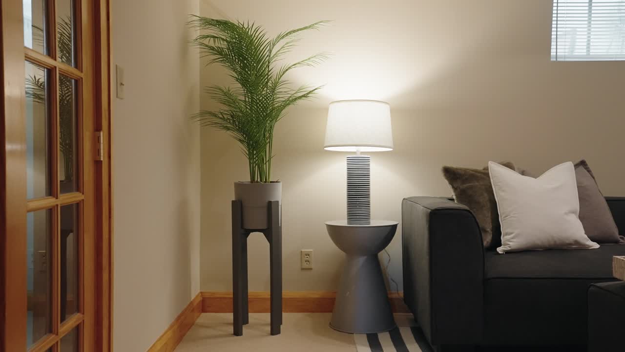 planta verde y una lámpara moderna en una mesa lateral junto a un sofá en una habitación familiar