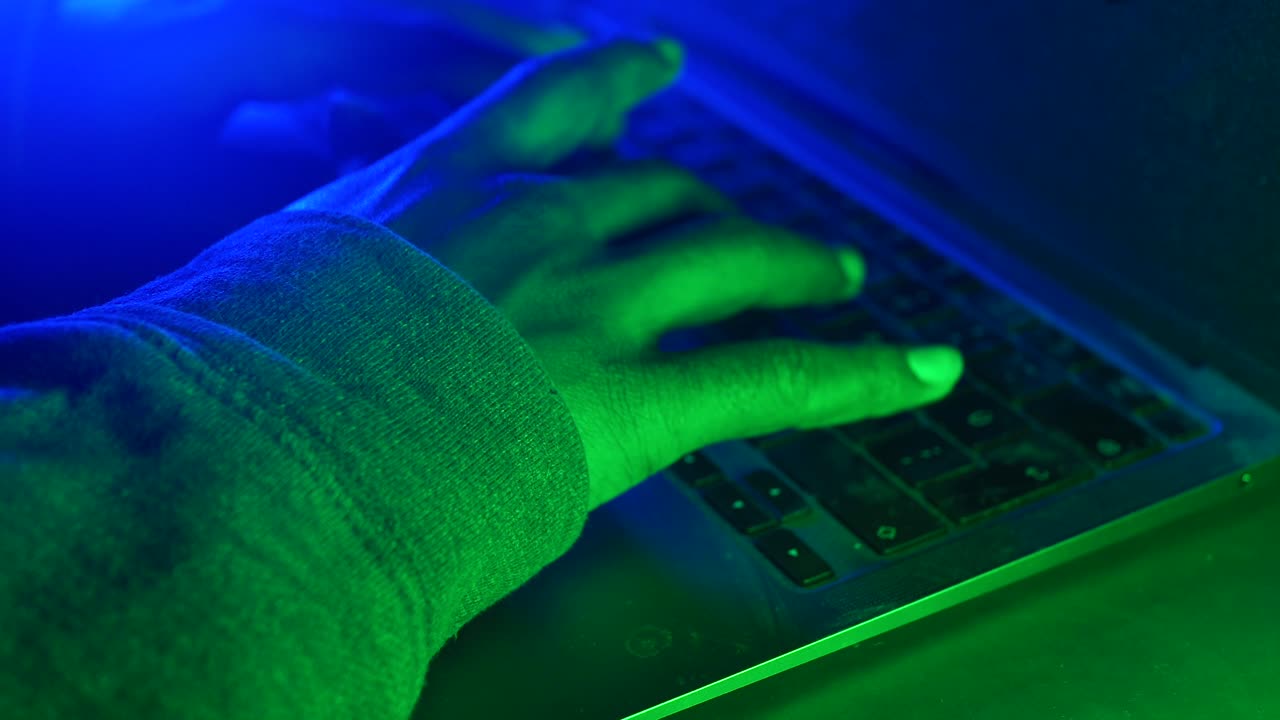 Person Typing on a Laptop in a Dark Environment