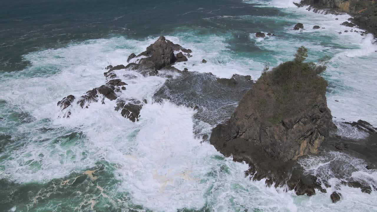 Pemandangan udara ombak pasang menerjang pulau karang dengan batu besar menjulang