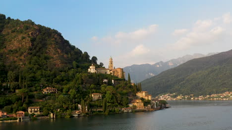 revealing drone shot of chiesa di santa maria del sasso in switzerland flying over lugano lake