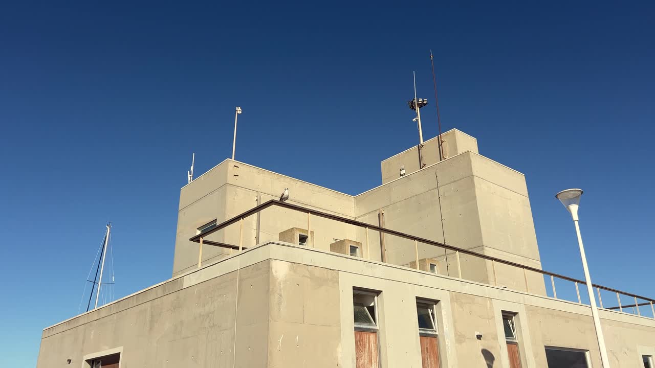 A coastal building with a modern architectural design against a clear blue sky. Mediterranean architecture, coastal living, contemporary design concept.