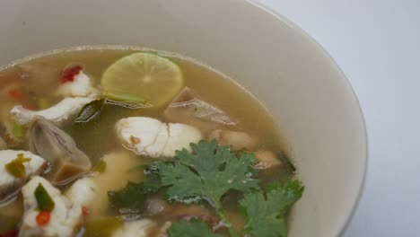 close-up footage of clear tom yum soup with sea bass and mushroom, the famous thai food well known by its aromatic and spicy taste