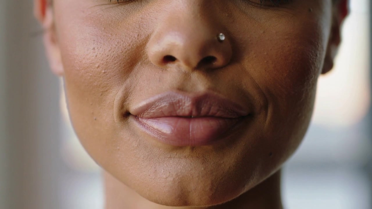 Starting speech, woman showing front teeth then shifting into gentle smile near window