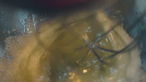 electric mixer spins and mixes eggs with sugar in bowl