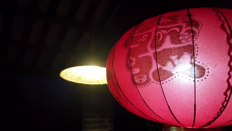 traditional red chinese lantern hanging next to the light in an old building in old town