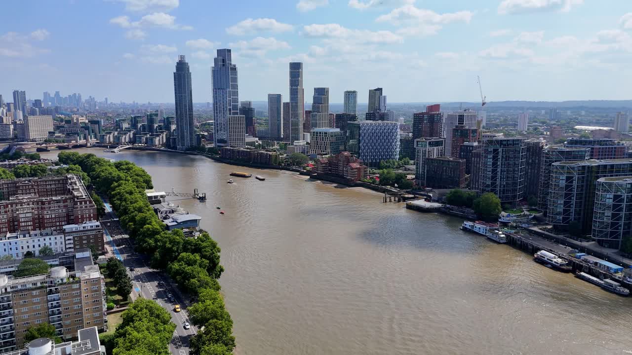 Aerial drone footage of the River Thames and Nine Elms district in London, showcasing modern riverside architecture, Battersea Power Station, and city skyline under clear summer skies