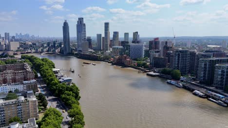 aerial drone footage of the river thames and nine elms district in london, showcasing modern riverside architecture, battersea power station, and city skyline under clear summer skies