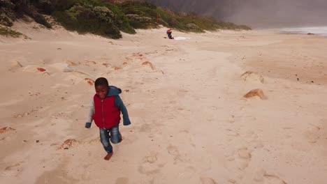 little boy running and playing on the beach in the winter time