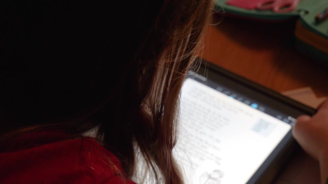 Girl reading her homework on a smart tablet