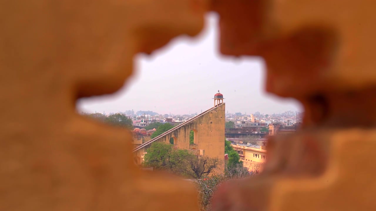 Una ripresa statica creativa del Vrihat Samrat Yantra, la meridiana in pietra più grande del mondo, incorniciata attraverso un'apertura a forma di stella in un muro di pietra presso l'osservatorio Jantar Mantar a Jaipur