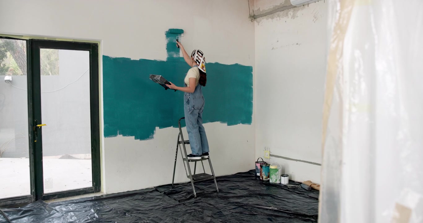 Jovem mulher pintando uma parede com um rolo em um quarto