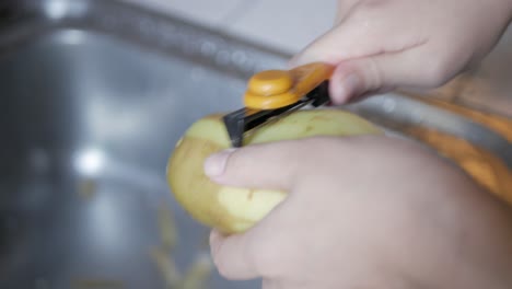 hand using peeler to peel potato skin preparing for cooking