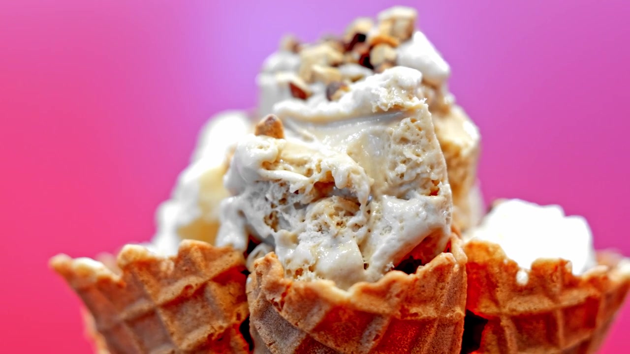 Primo piano di una grande pallina di gelato cremoso servita in un croccante cono waffle dorato, che mostra una consistenza liscia e una presentazione invitante del dessert