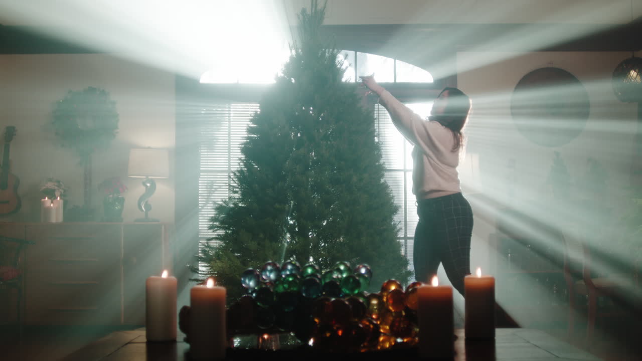 Woman Decorating a Christmas Tree with Candles and Light Rays