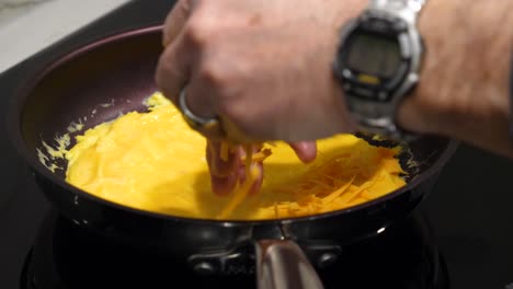 making an omelet - adding cheese to egg