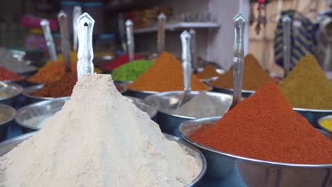 pan from left to right close up through colourful piles of mixed herbs - spices in outdoor store market scene in goa palolem beach south india