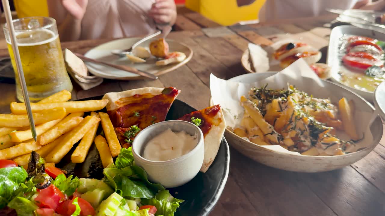 Casual dining scene with diverse dishes and drinks at a beach club in Phuket. Warm lighting enhances the relaxed atmosphere