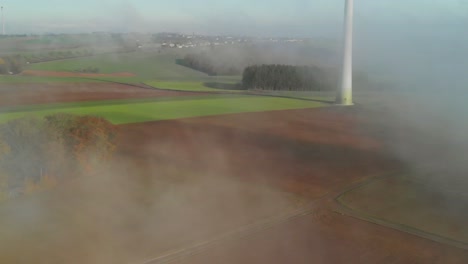 reveladora toma aérea de una zona rural de luxemburgo que muestra un aerogenerador, durante una mañana con niebla