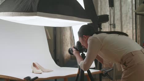 asian female photographer checking the photos of women's shoes after taking them in home studio